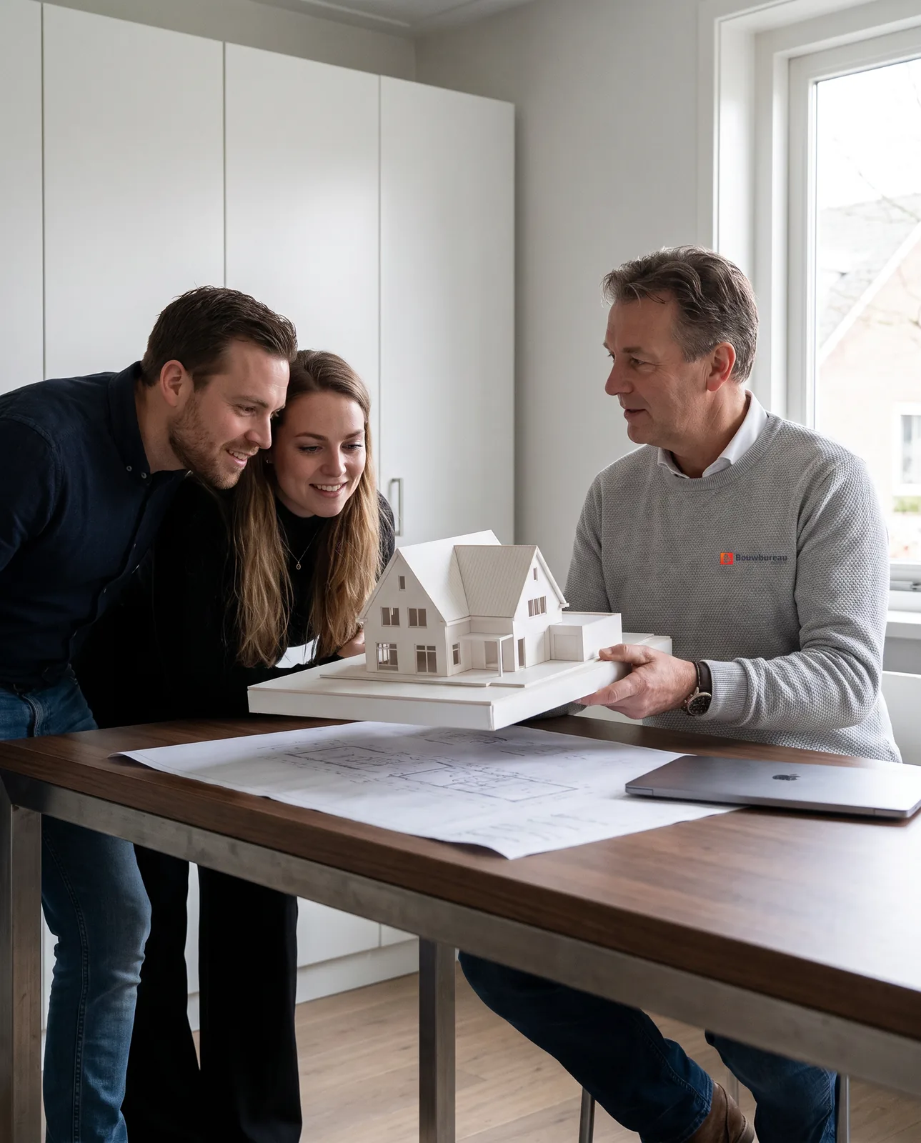 Een adviseur van ons en de toekomstige bewoners bekijken samen de tekening en de maquette van hun nieuwe huis