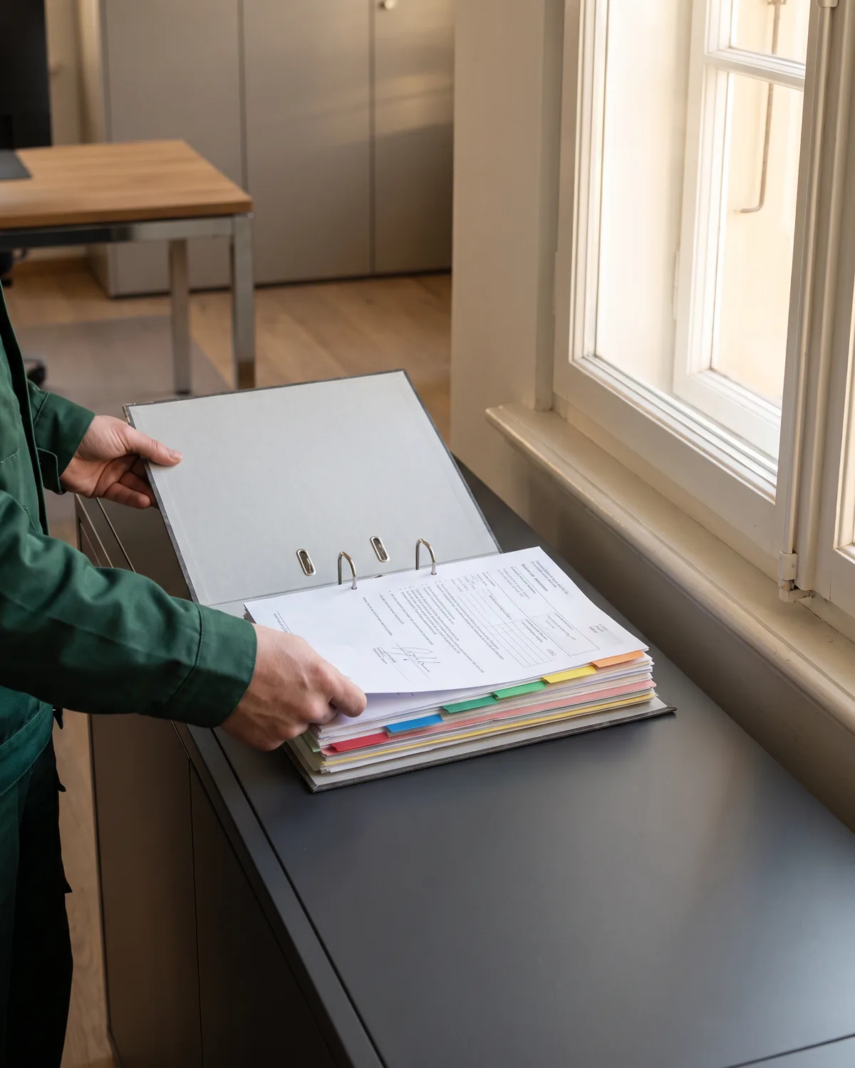 Handen zetten een getekend meerwerkformulier in een grijze ordner