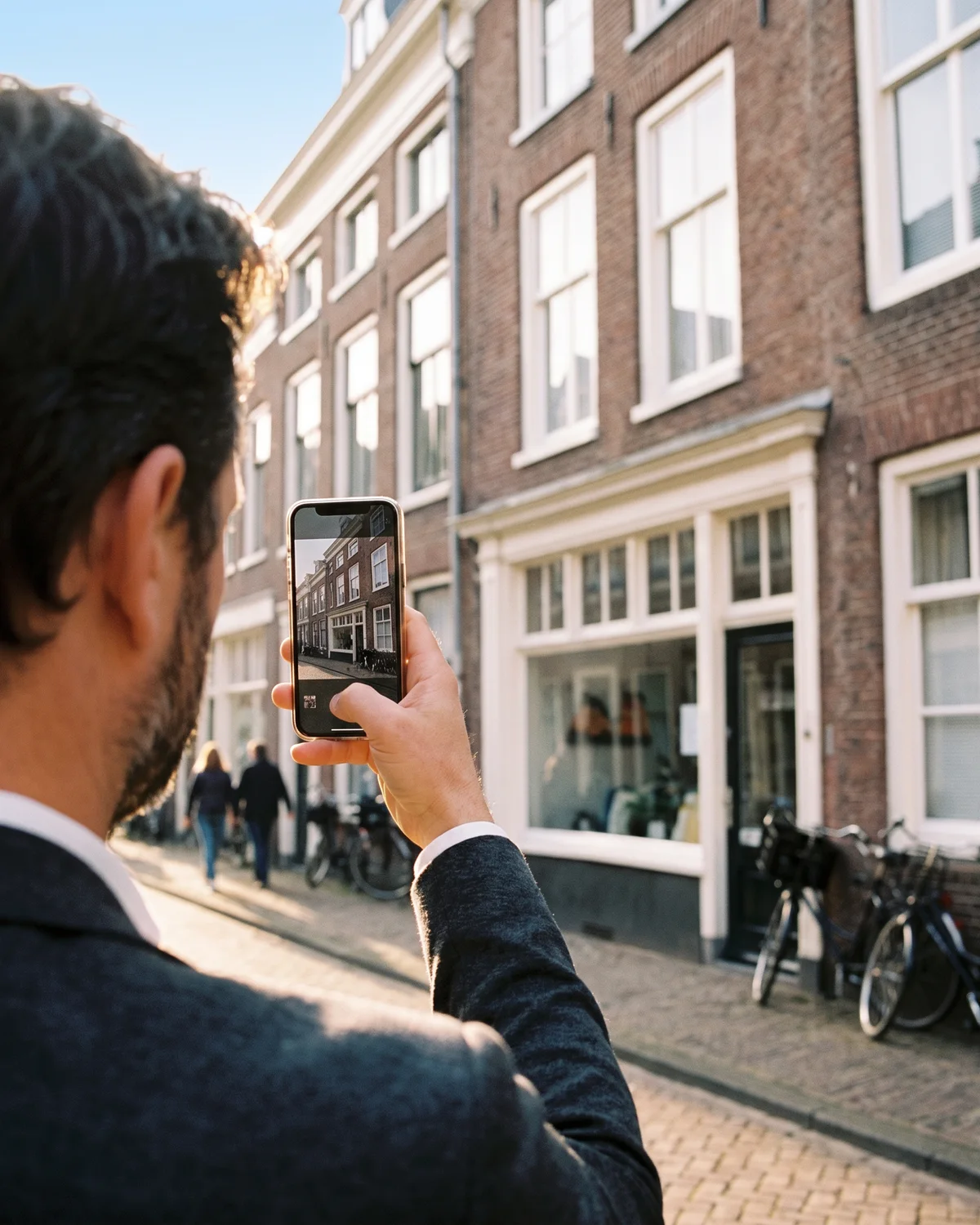 Een man fotografeert een gevel in een stadsstraat